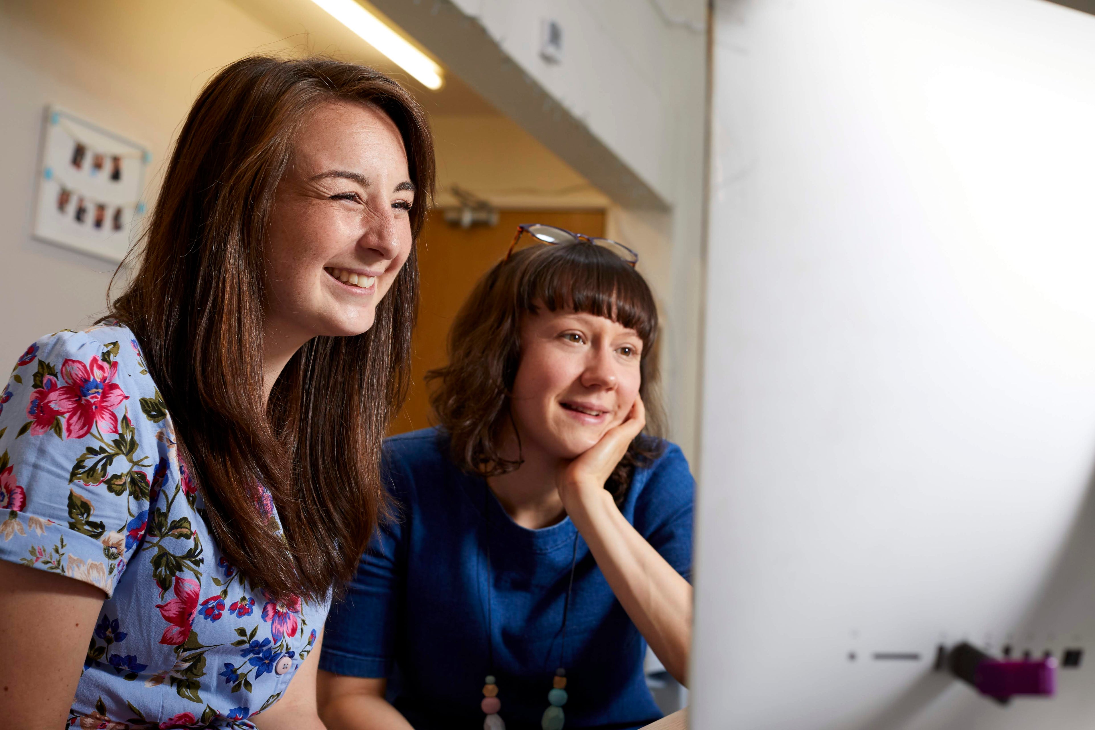 Two women looking at a computer screen together in an indoor setting.