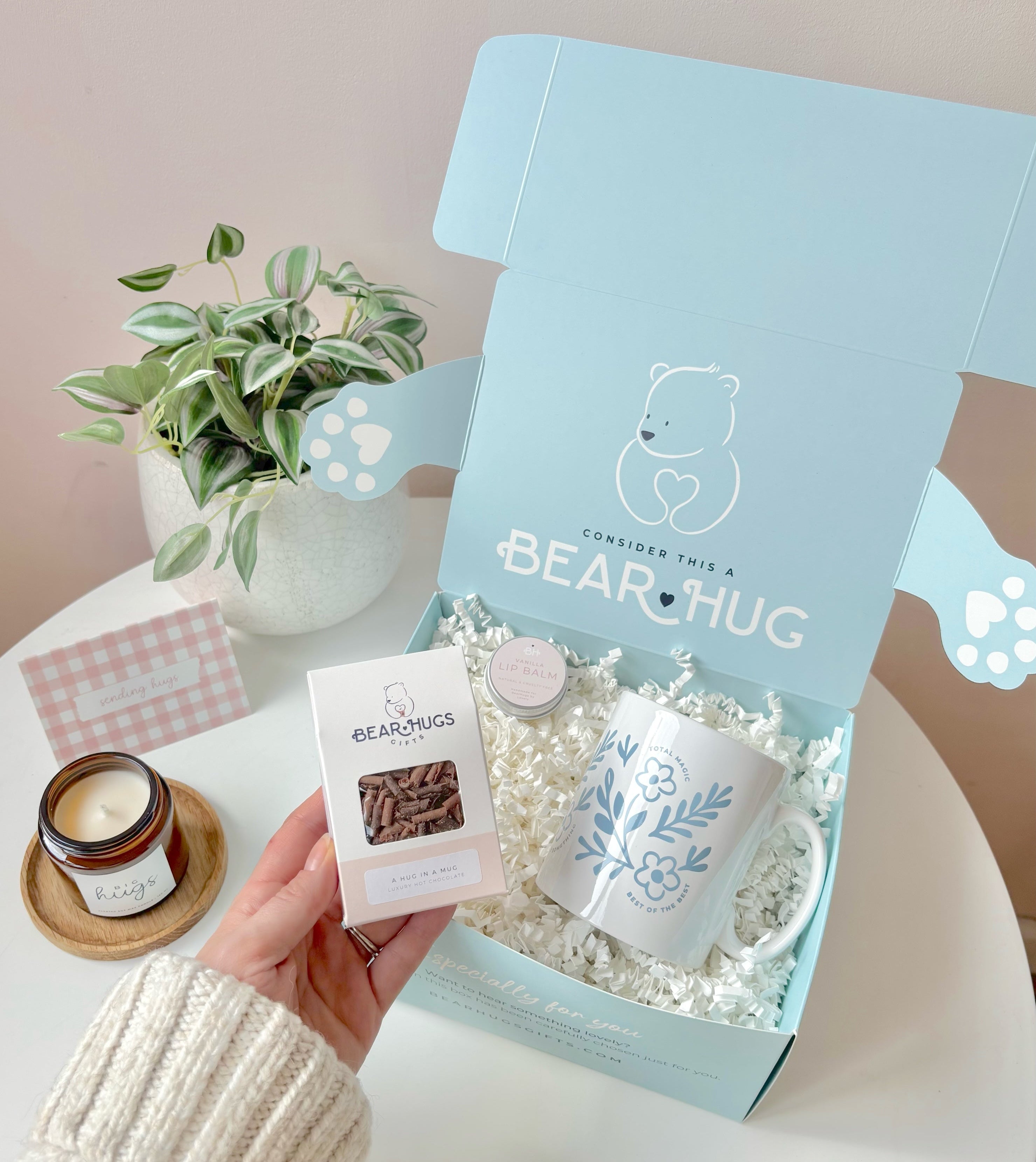 Gift set with a mug, small box, and card in a 'Bear Hug' branded box on a table.