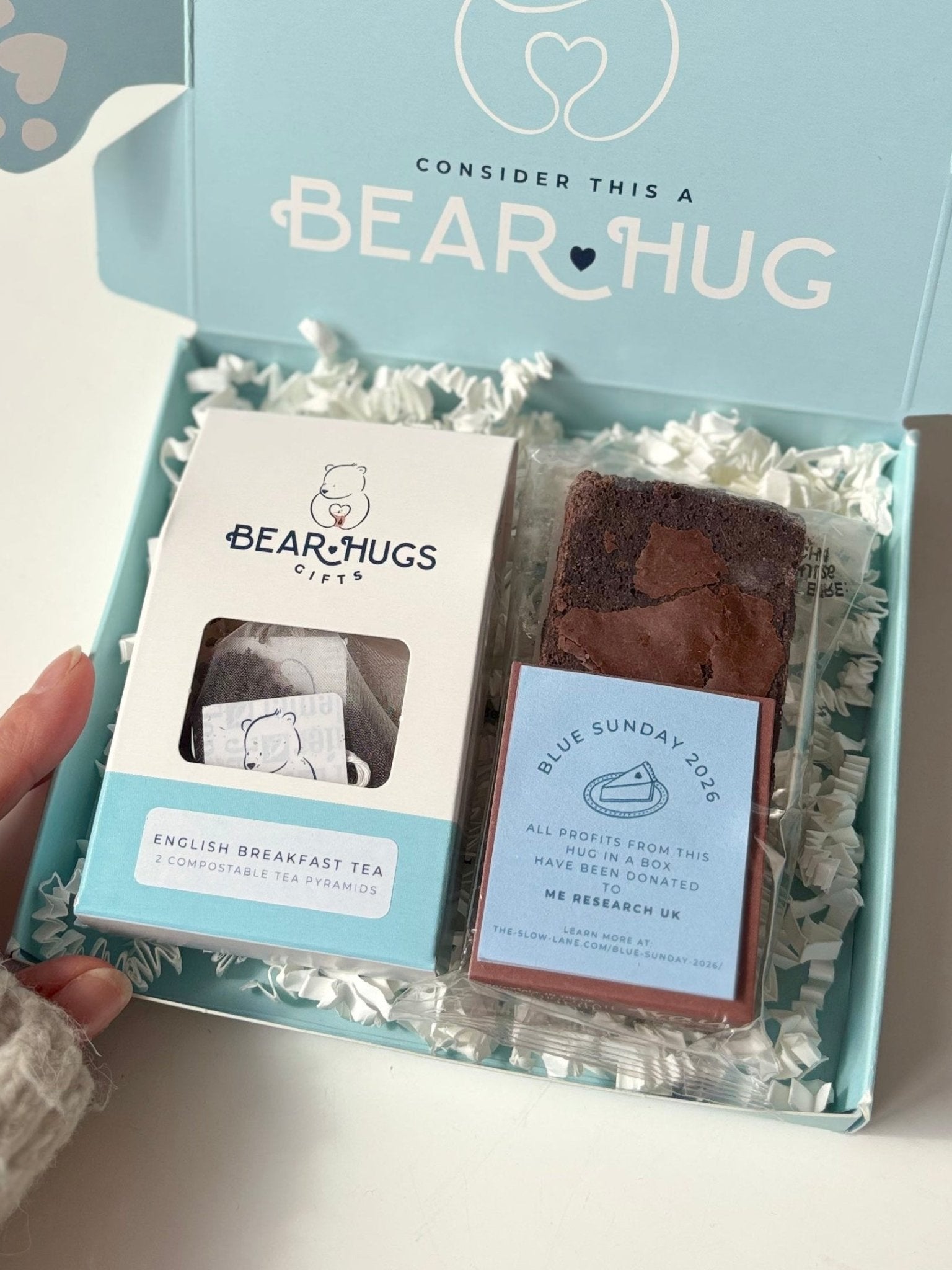 Bear Hug product packaging with two items on a white surface, accompanied by a plant in the background.