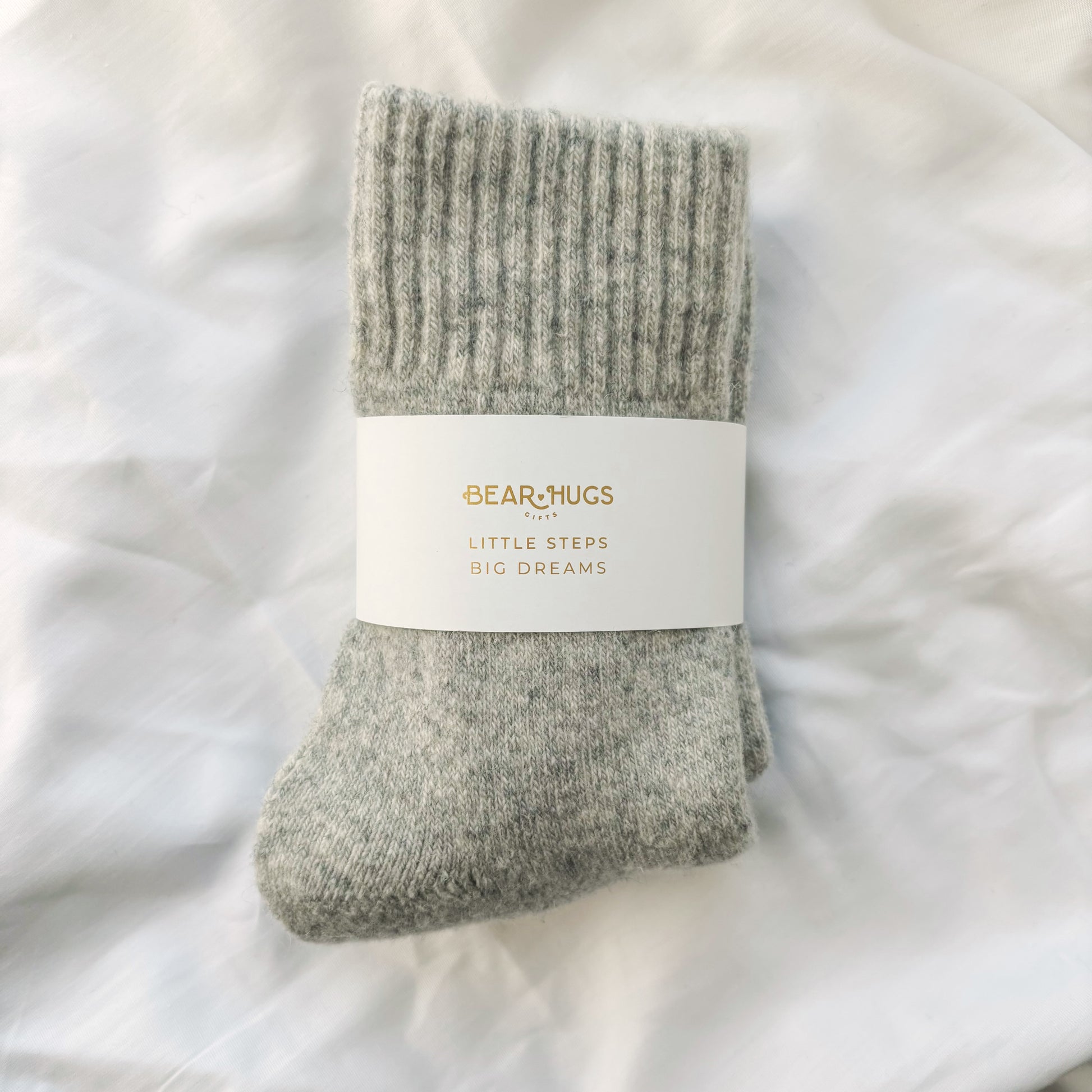 Gray baby sock with a label on a white blanket