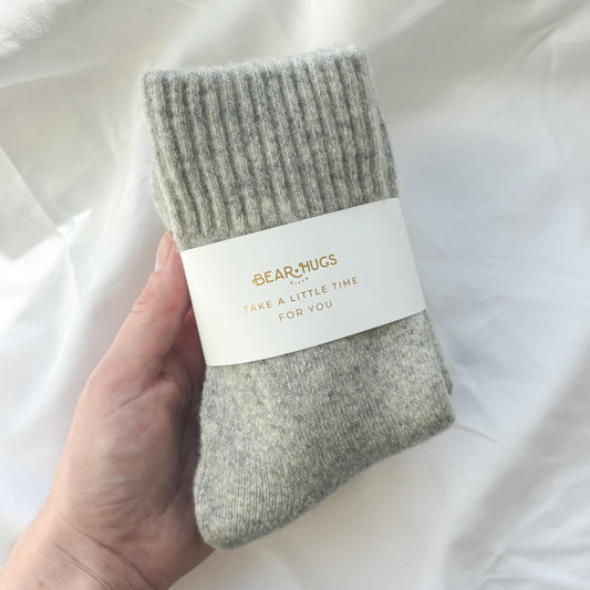 Gray socks held by a hand with a label on a white background